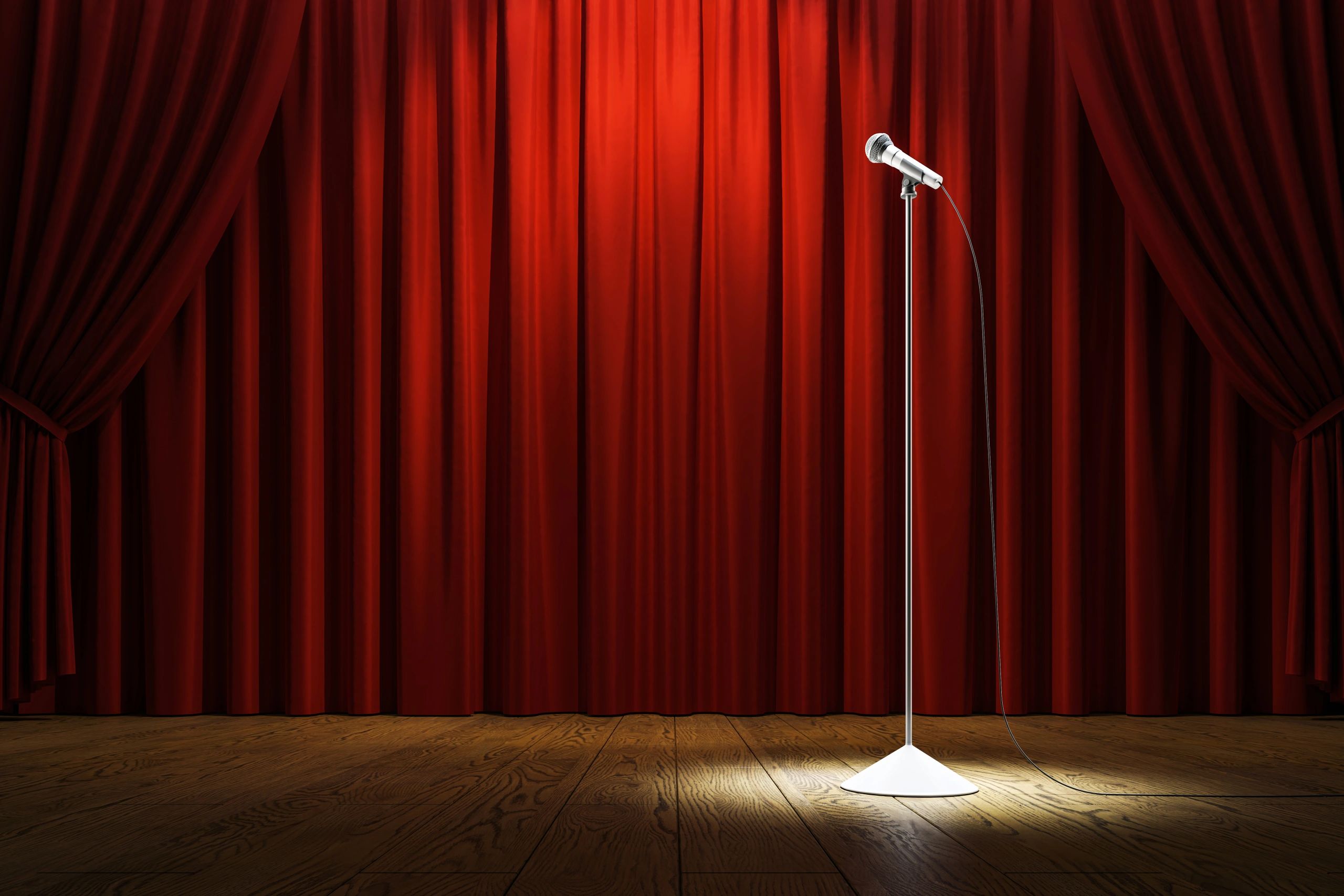 Microphone stand on stage with red curtains and spotlight