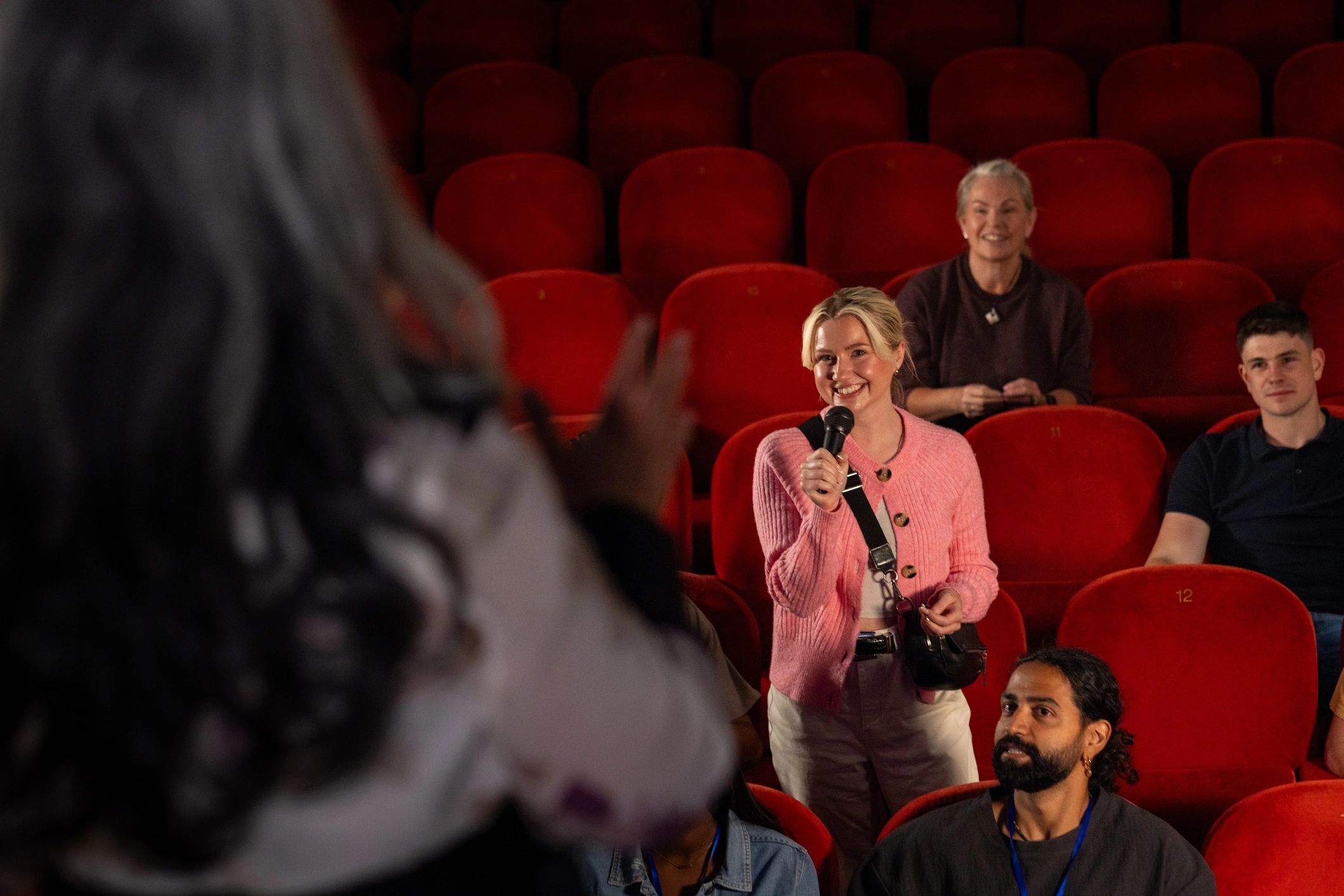 Smiling audience member holding a microphone in a venue