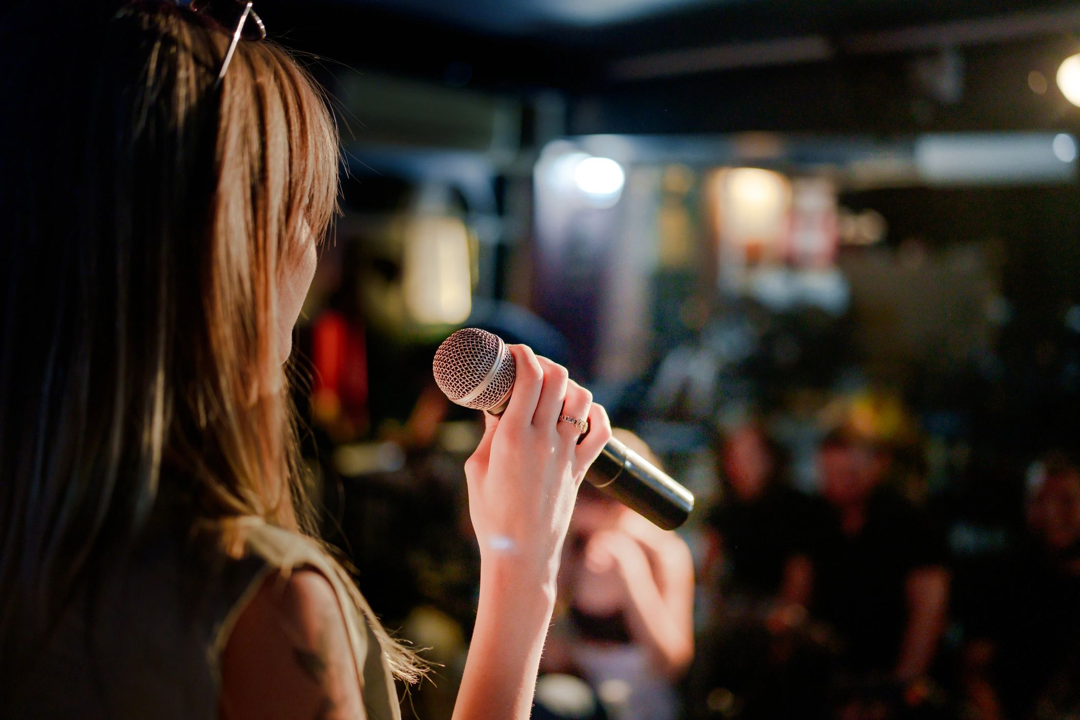 Performer holding microphone on stage facing audience