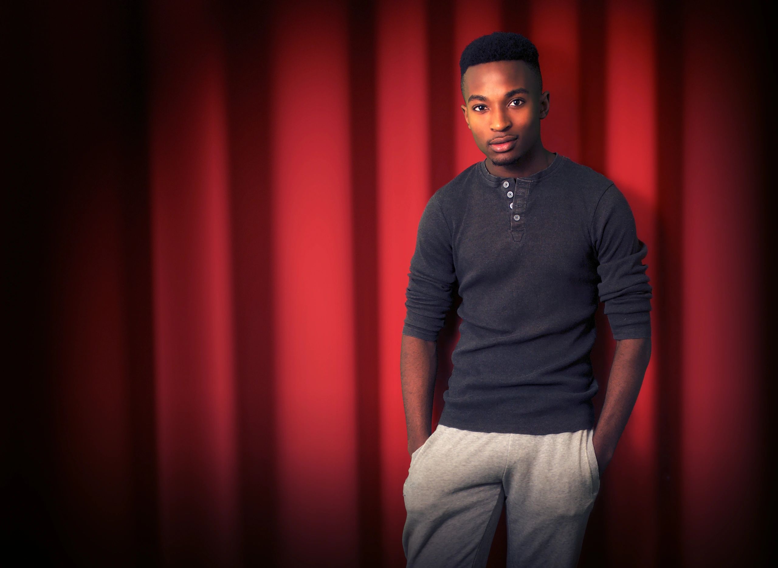 Standup performer on stage in front of a red curtain